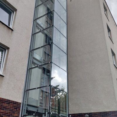 Prosklená šachta moderního výtahu vně budovy